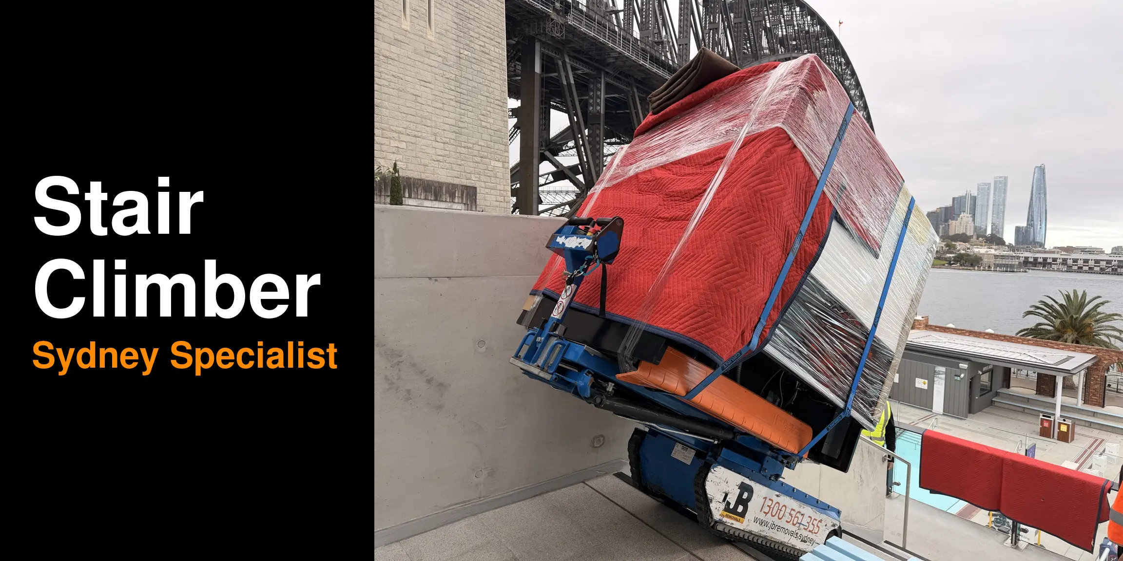Original JB blue tracked stair climber and wrapped load beside the Harbour Bridge