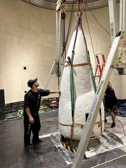 Tall marble lower section with slings beneath a gantry