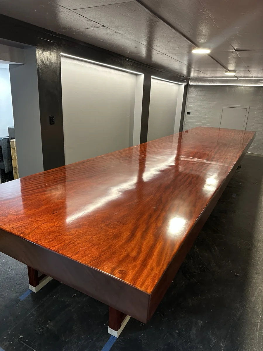 Long polished timber table in its final position on stands in an indoor room