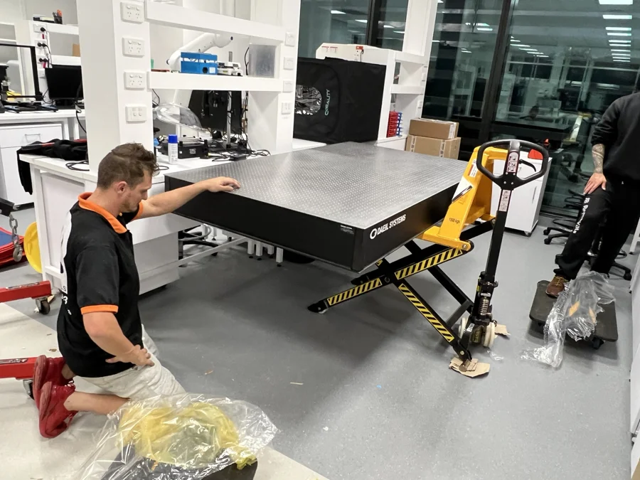 DAEIL SYSTEMS optical table supported on a high-lift scissor pallet jack while the JB team works in a university laboratory